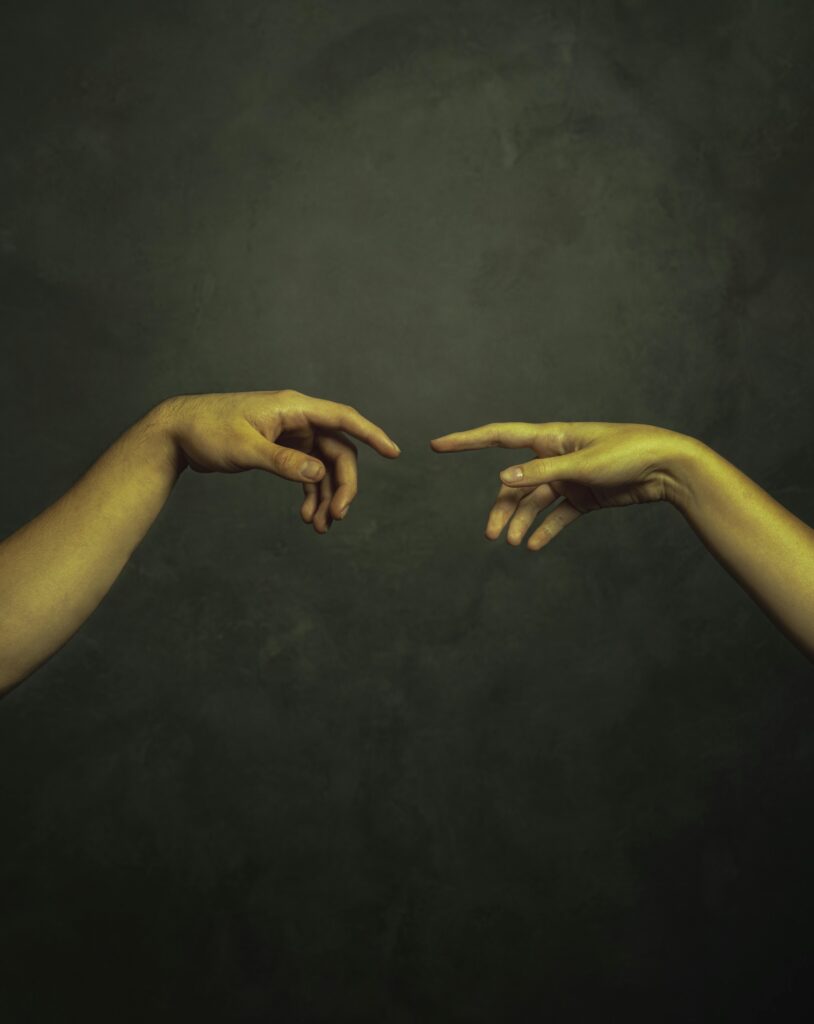 Two hands reaching towards each other against a dark background in an artistic style.